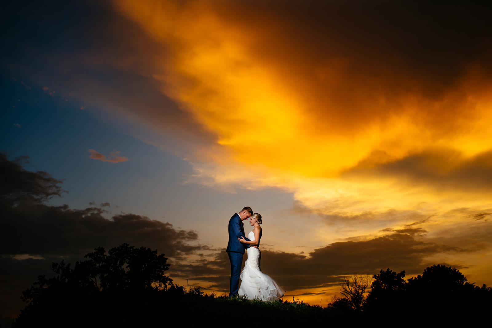 A couple embracing at sunset under a glowing orange sky