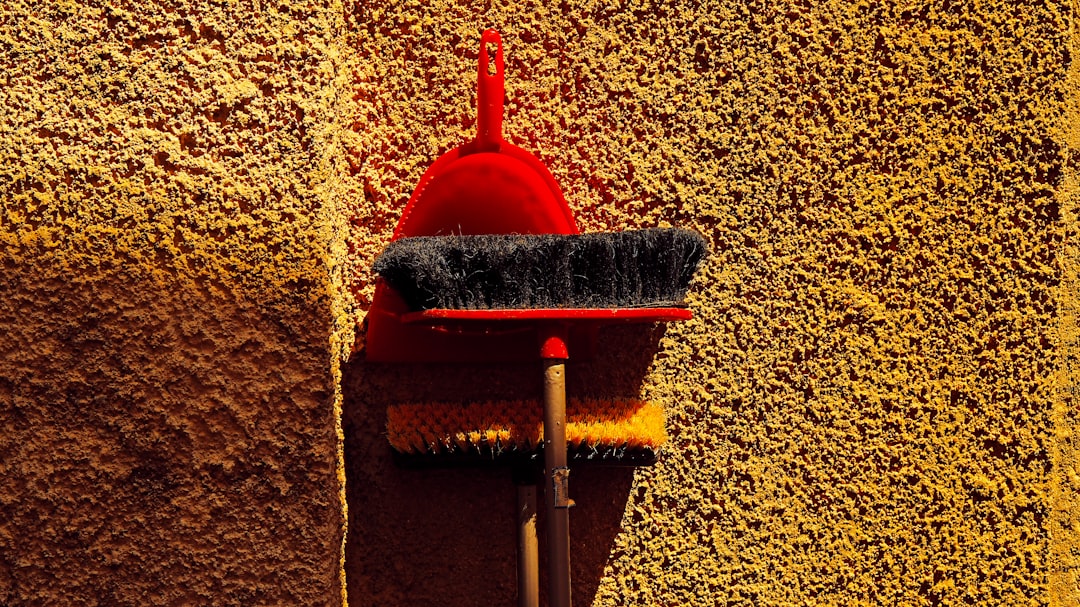 Red dustpan and broom leaning against wall — Photo by boris misevic on Unsplash